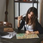 people holiday tourism concept picture attractive young brunette female office worker sitting her workplace biting glasses looking world map her desk planning vacations 343059 185